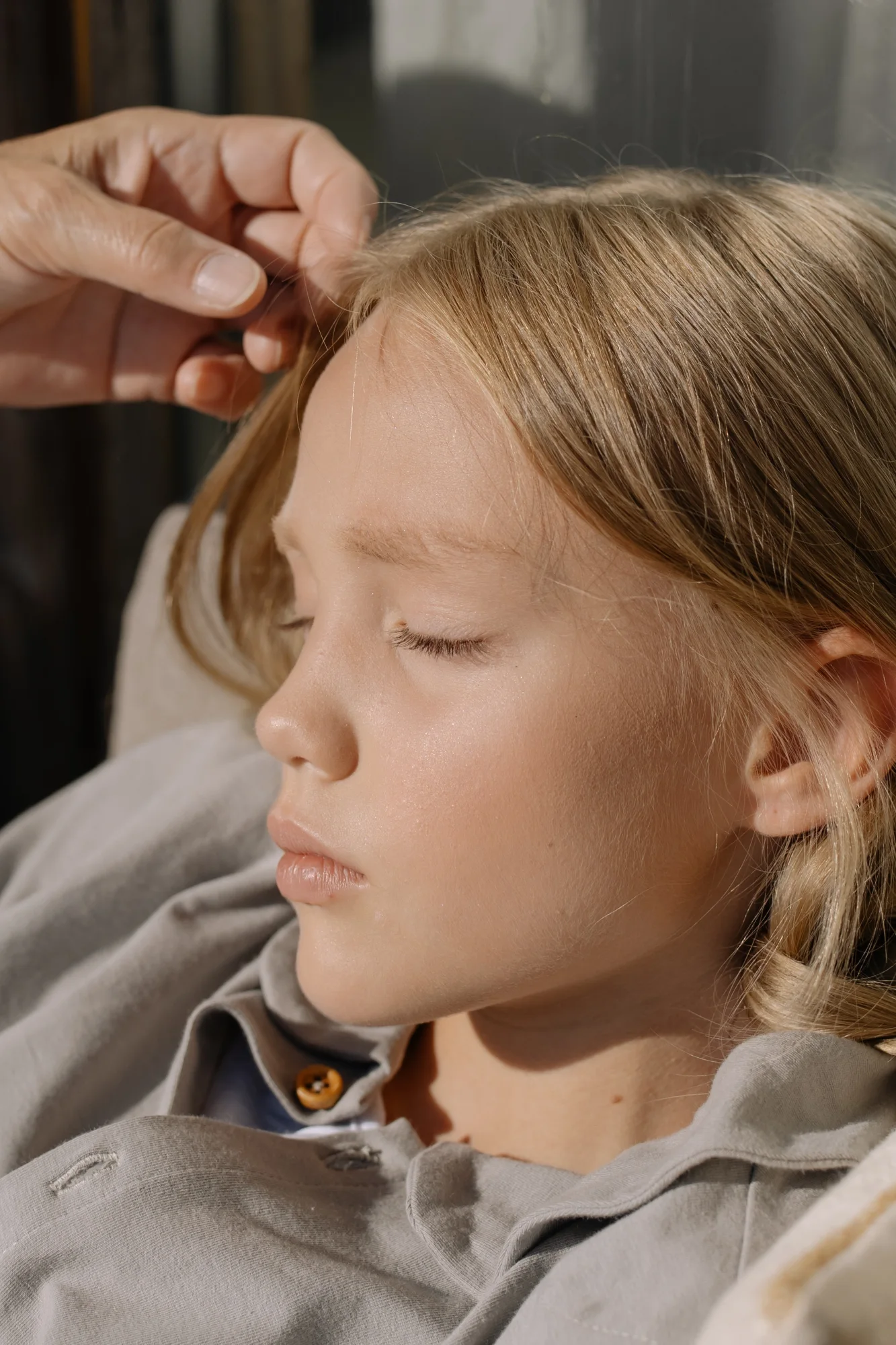 An adult hand resting gently on a child's hair