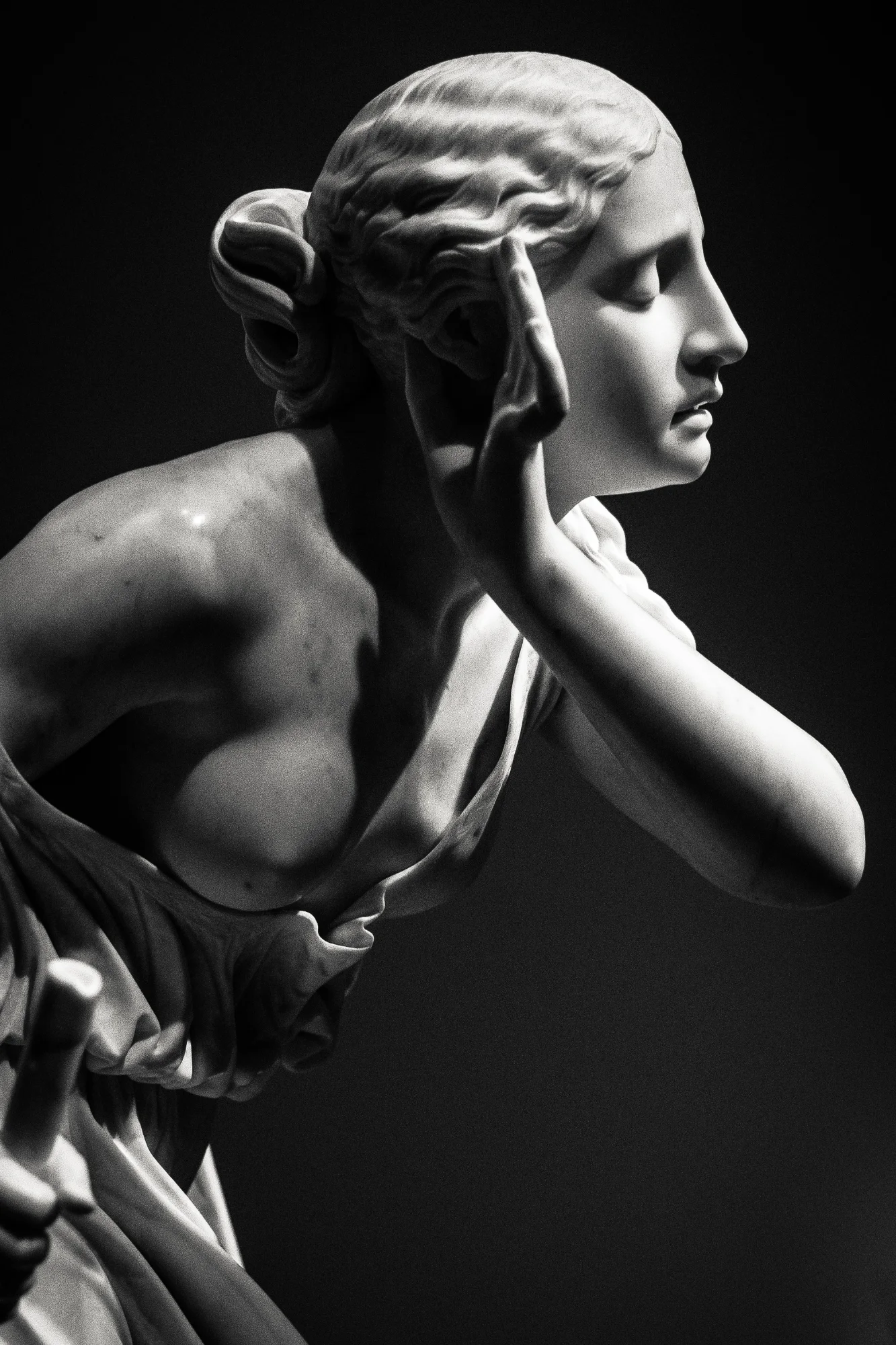 A sculpted figure, head tilted, listening